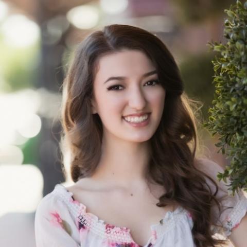 Headshot of Danielle. She has long brown hair. She is wearing a floral shirt. She is smiling. 