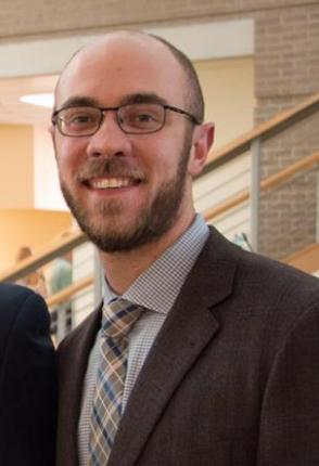 Christopher Menking in a suit, smiling.