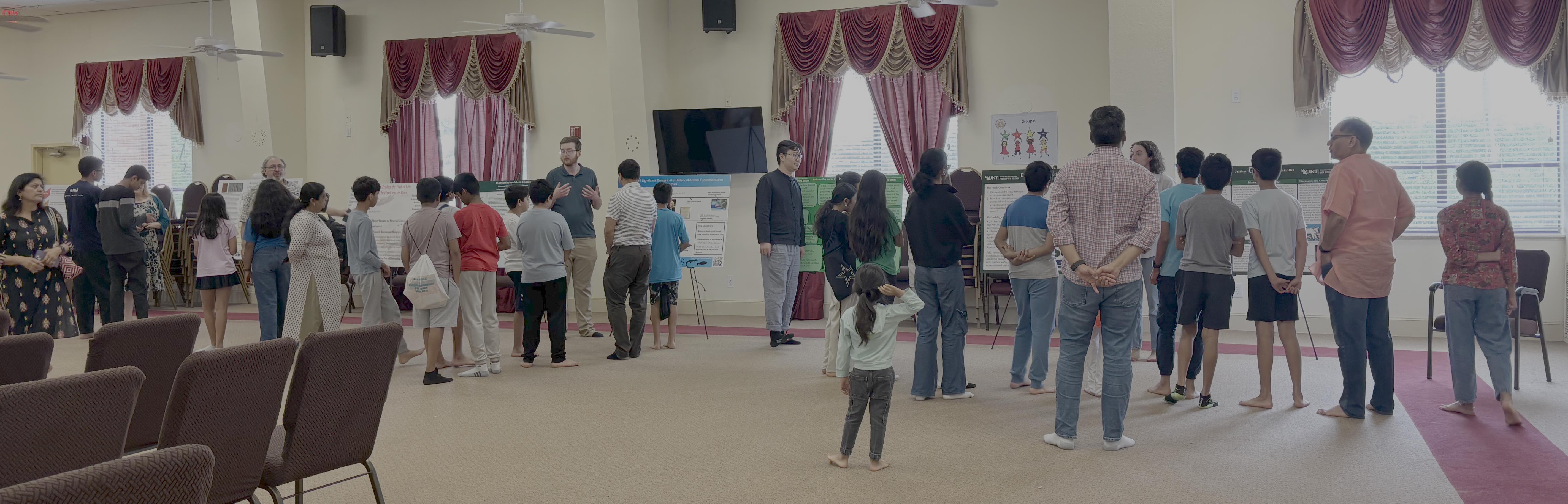 People stand in a large room to look at posters.