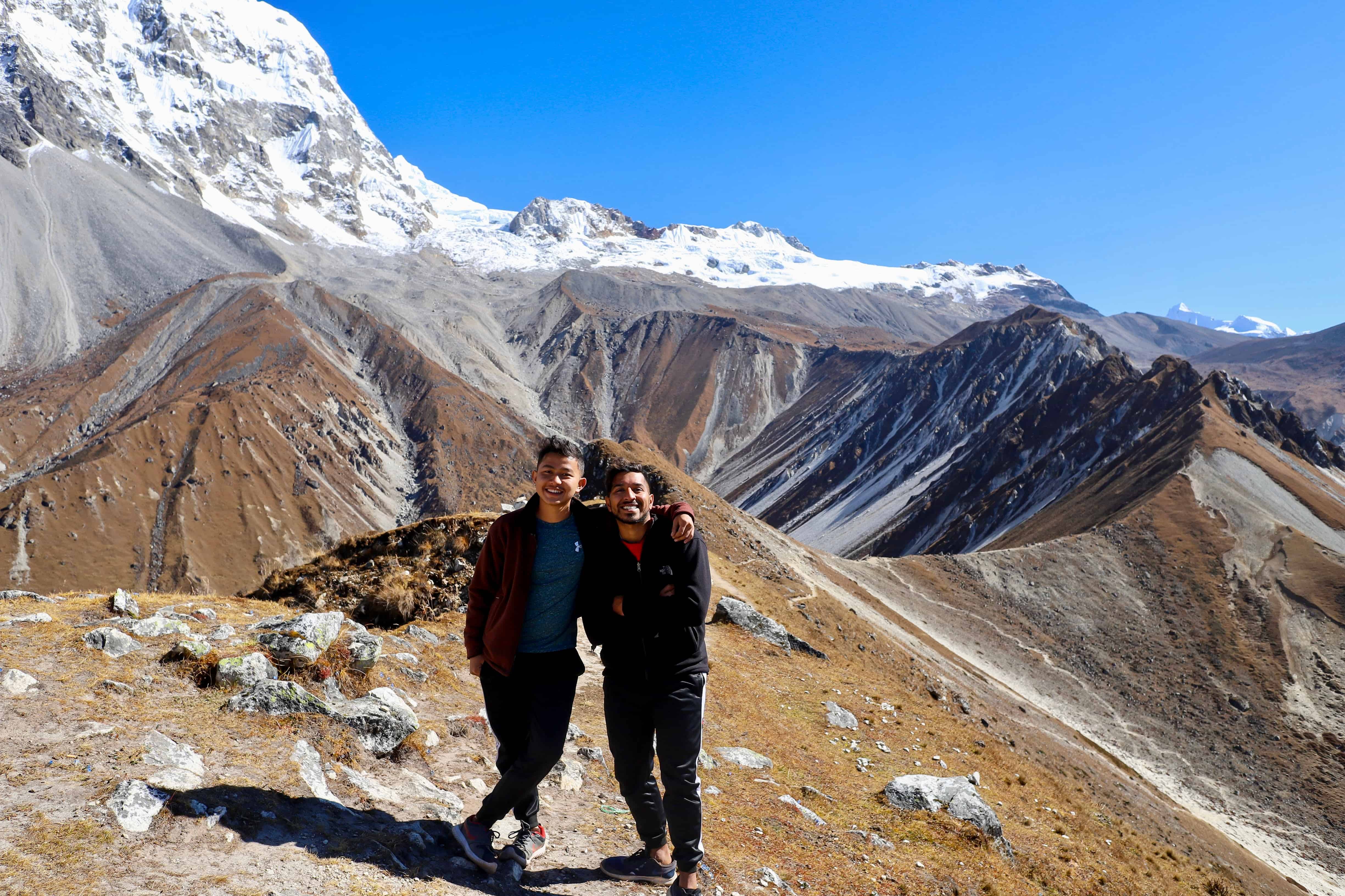 A photo of Aerin and his Peace Corps brother in the mountains, with snow capped mountains extending even higher behind them.