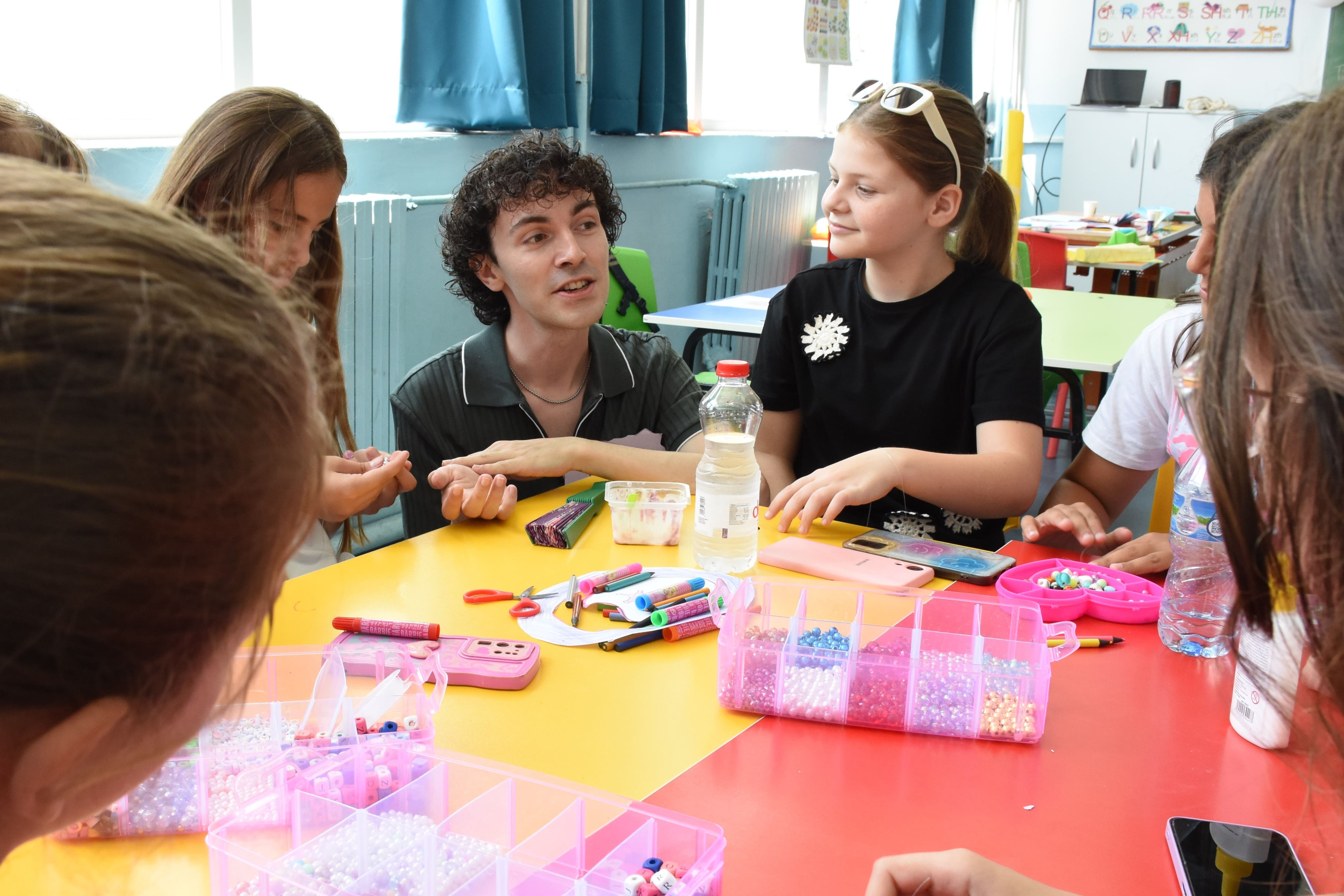 Jordan sits with a group of girls working on arts and crafts projects