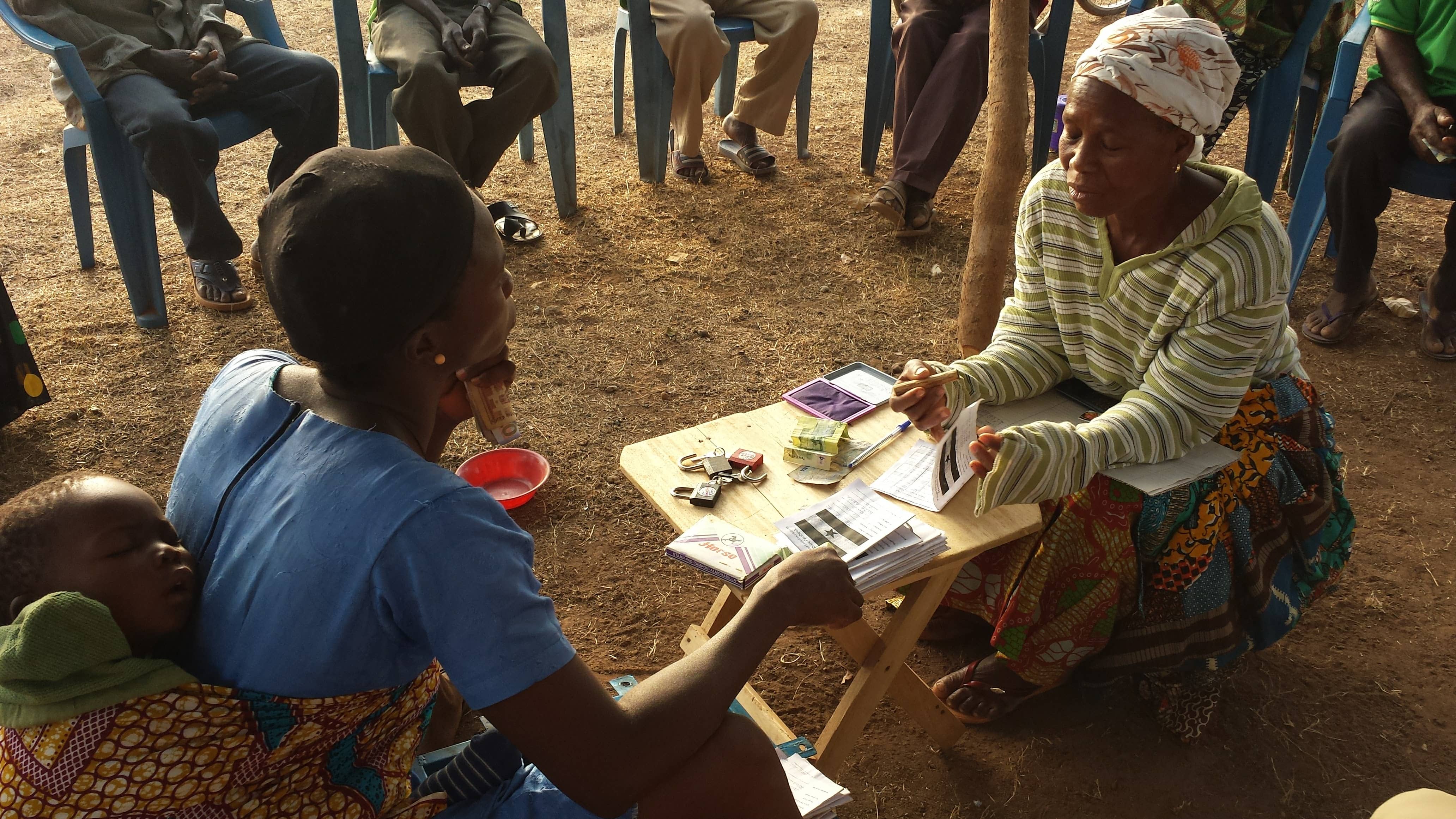 Locals from Ghana sit around a table working on a project.
