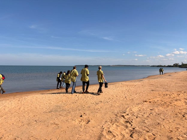 A group of students searching a beach for plastic pellets