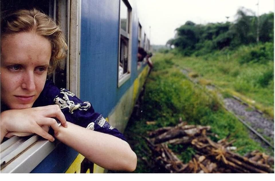 Lura looks out the window of a train.