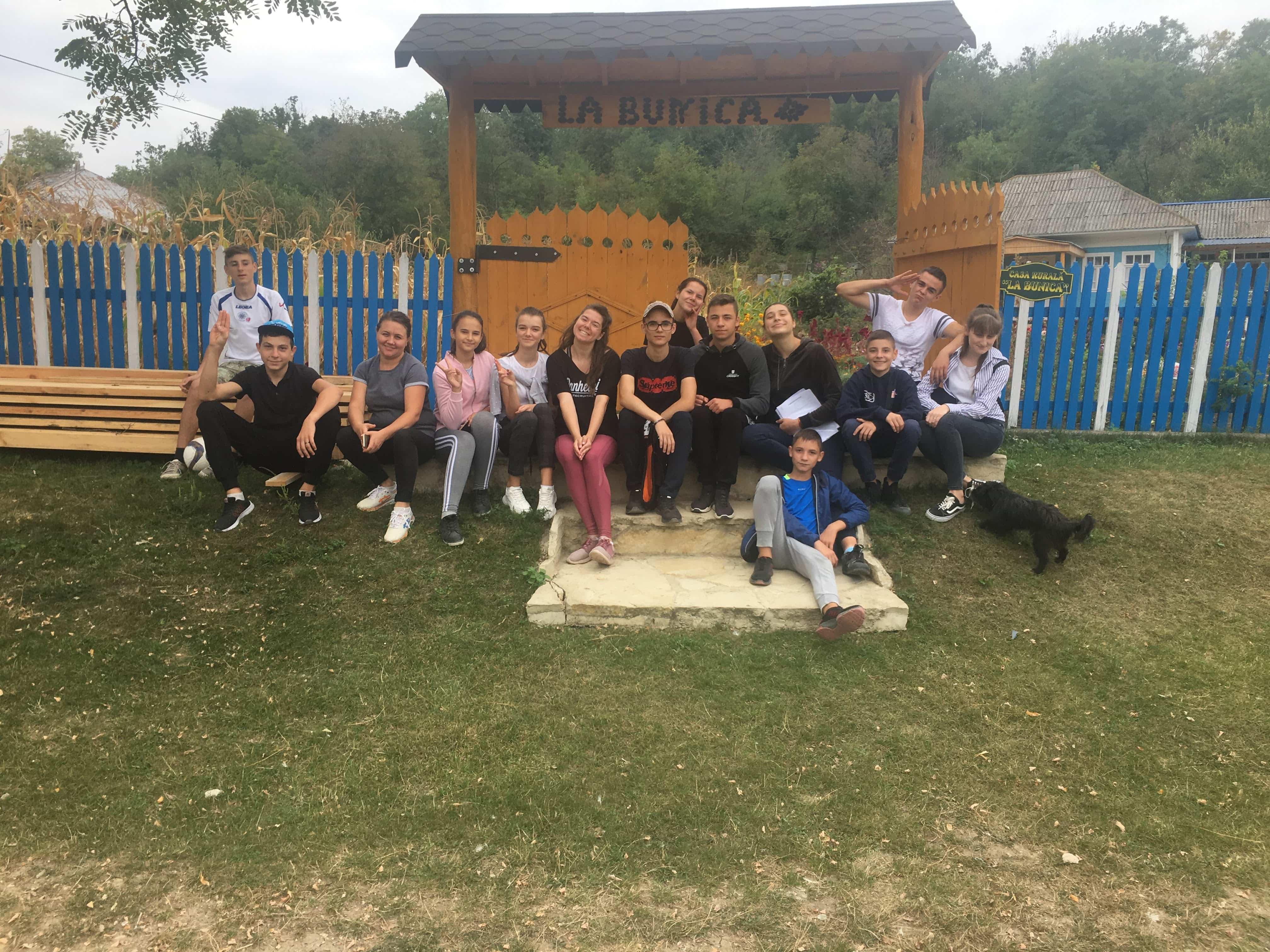 A picture of Moldovan children sitting in front of an archway that reads "La Bunica"