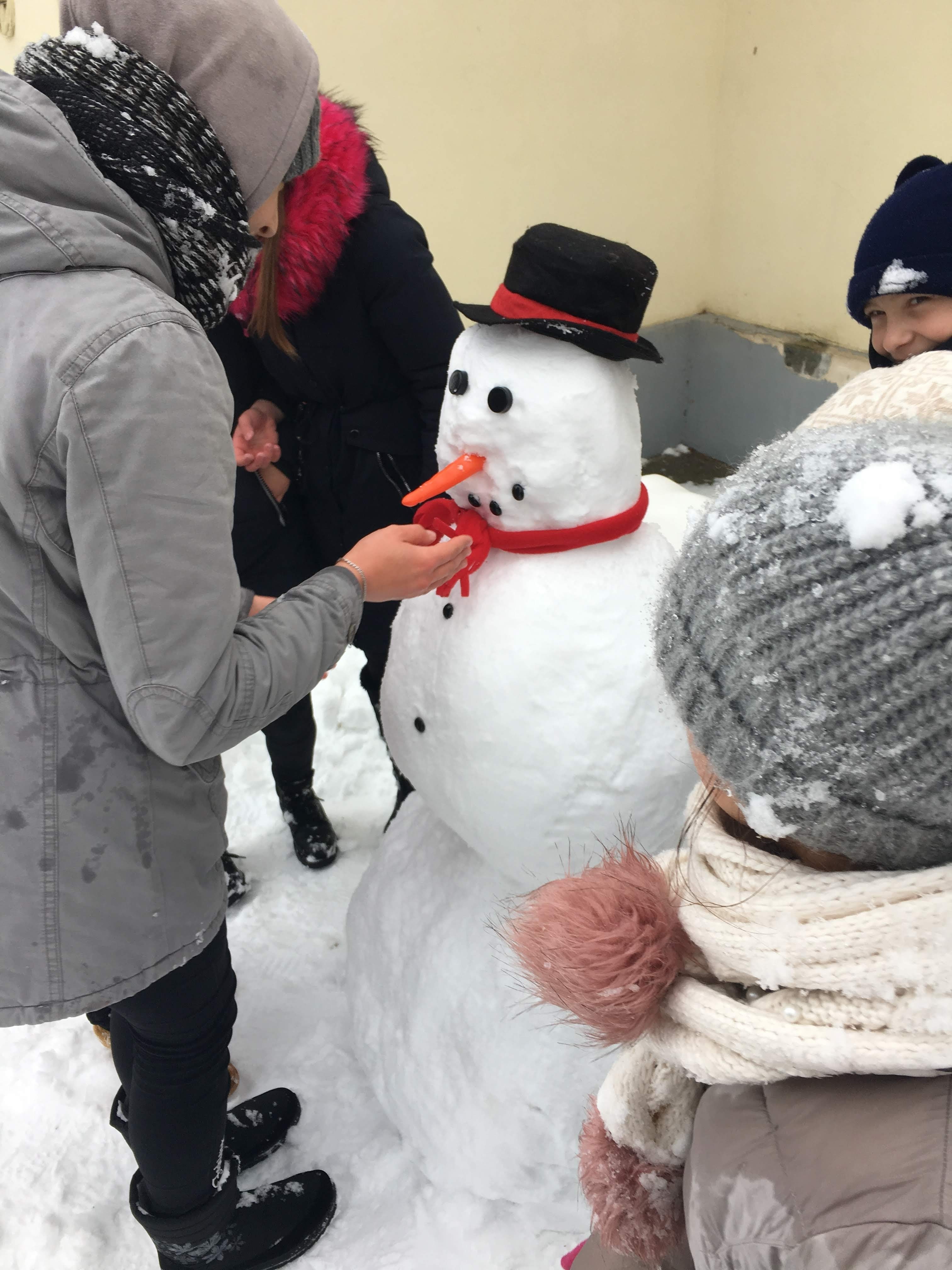 Local Moldovan children made a snowman with an orange carrot for a nose.
