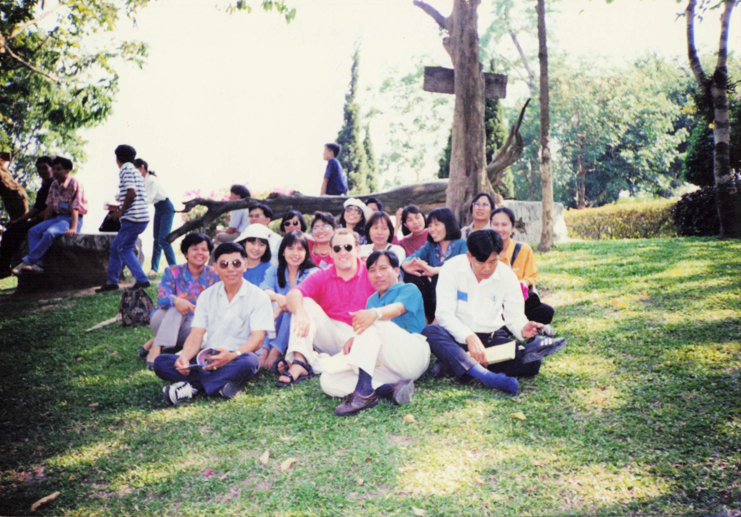 Matthew sitting on a hill surrounded by Thai residents.